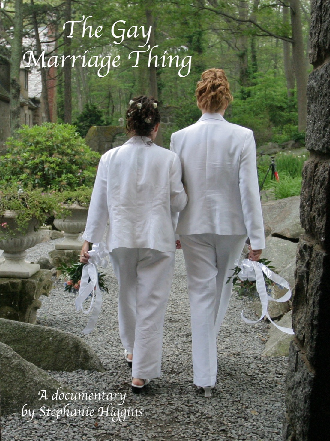Wedding photo, two women back to the camera stand and hold hands through a stone arch.